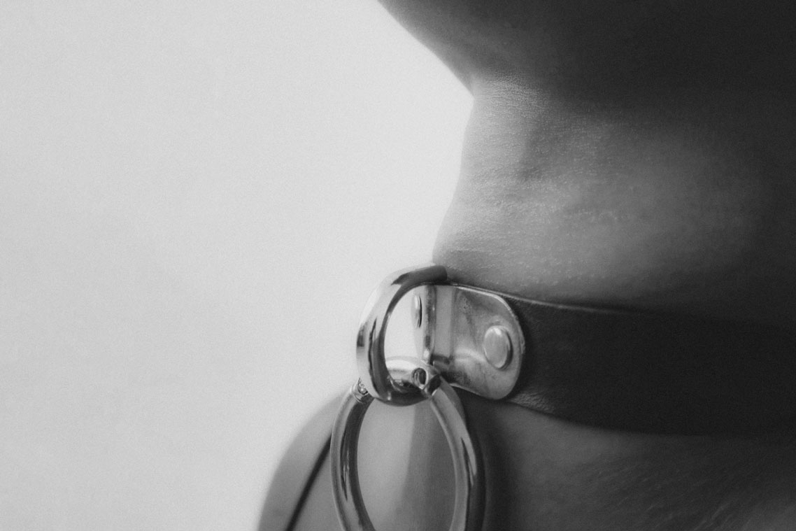 Intimate couple in soft light, hand gently at neck, symbolizing trust and closeness